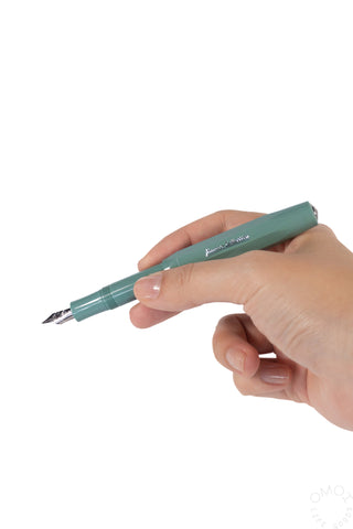 Sage green fountain pen held in hand, fine tip nib visible