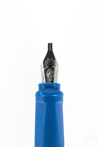Front close-up of metal calligraphy fountain pen nib on blue ink reservoir