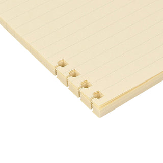 Corner view of cream refill pages with tabbed binder clips along the edge