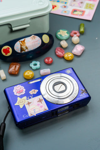 Blue camera decorated with colorful Lucky bears stickers, stars, and heart shapes