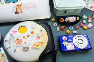 Pink sticker icons scattered on devices, featuring hearts, flowers, and cartoon shapes