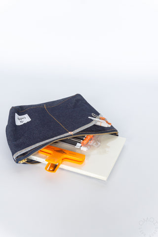 Denim double-pocket pouch with zip opening and orange tool accessories inside
