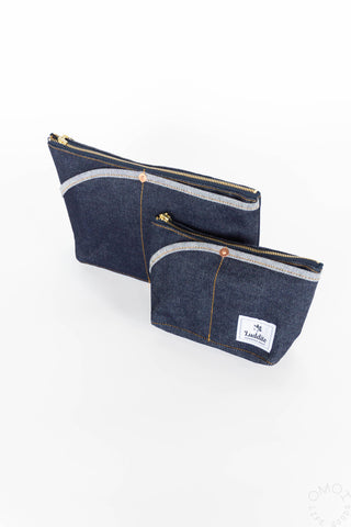 Two small denim zip pouches stacked, each with gold zipper and logo patch