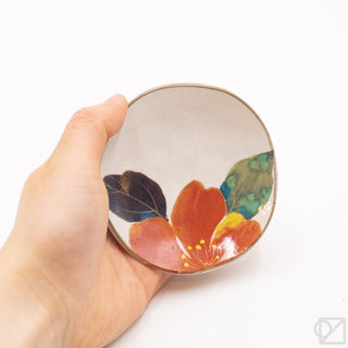 Mini ceramic plate held in hand, floral pattern in red and green