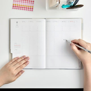 Blue A5 weekly vertical planner open with handwritten note on the schedule grid