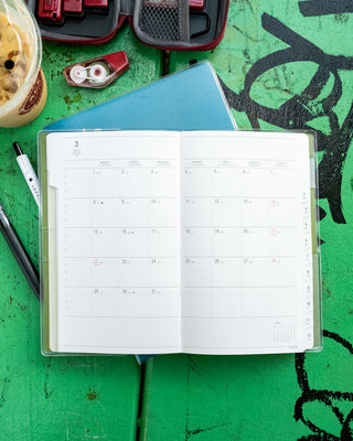 B6 slim weekly vertical planner, open showing month/week grid on both pages
