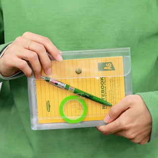 Clear general purpose case pouch held with notebook and highlighters; brass snap button.