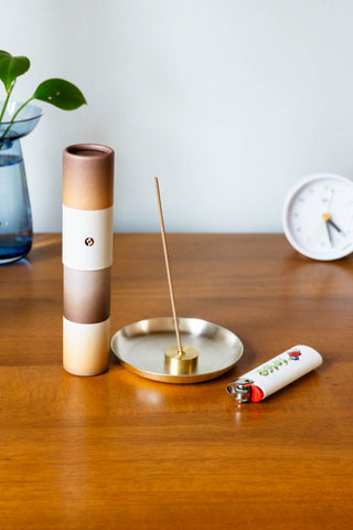 Gradient incense tube with bundle of wooden incense sticks, standing on a tabletop