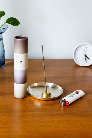 Tall gradient incense tube with bundled brown sticks and open end for burning
