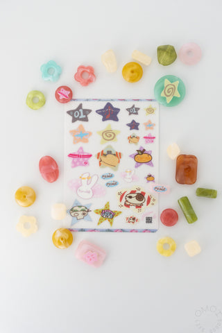 Clear sticker sheet with colorful character stickers surrounded by small loose pieces