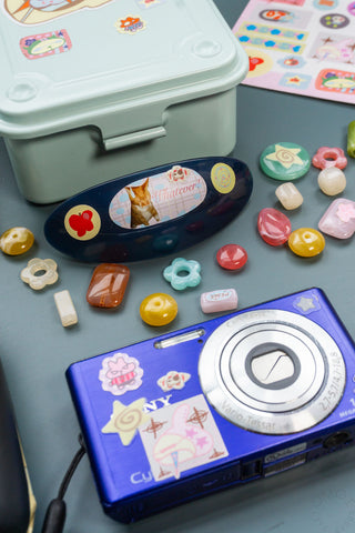 Camera-shaped sticker case with colorful cartoon sticker icons and cutout designs