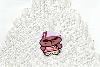 Cartoon character patch on white textured fabric, dog in cap with sunglasses