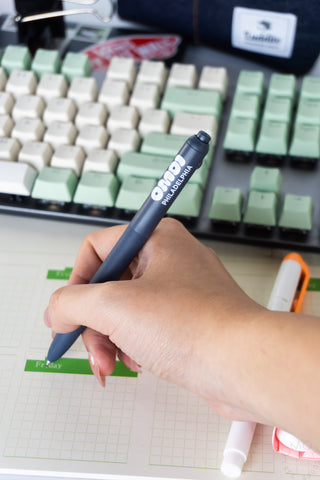 Blue gel pen held in hand, OMOI Philadelphia logo visible on the barrel