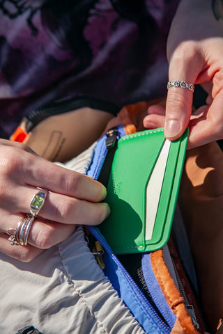 Green card slip wallet partially open, showing card slots and a light interior