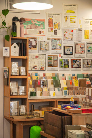 OMOI's TRAVELER's section of the sales floor during the Stamp Caravan event. The wall is full of photo samples from the TRAVELER's team of their notebook spreads, along with the stock below.
