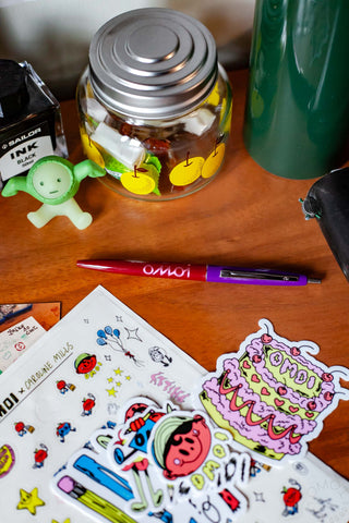 OMOI Shop Pen dark berry capped pen on wooden desk near stickers