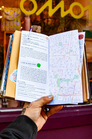 OMOI's short trips guidebook opened to a city map and schedule text page.