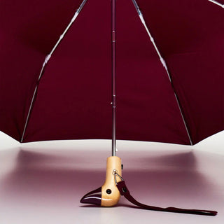 Maroon umbrella canopy with duck-shaped wooden handle base and black strap