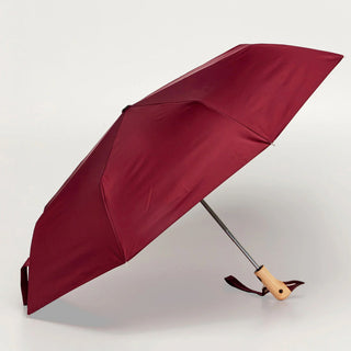 Maroon compact umbrella open with duck-shaped wooden handle and carrying strap