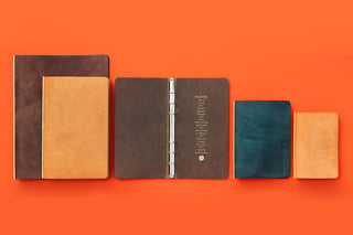 Mini leather ring binders in brown, navy, and tan with metal rings