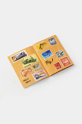 Yellow kraft passport-size notebook with vintage travel sticker collage
