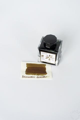 Bottled ink with black cap and Shirakashi label, plus brown ink swatch card