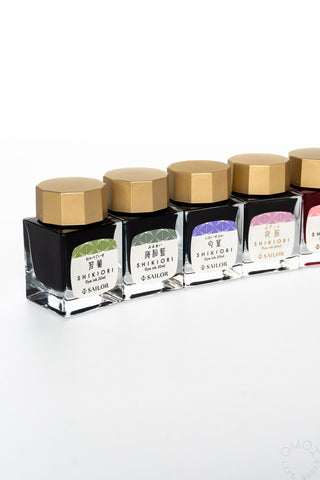 Bottled ink set in clear square bottles with gold caps, shown in a lineup