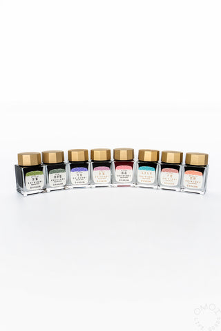 Bottled ink set with multiple colors, each in a clear glass bottle with gold cap
