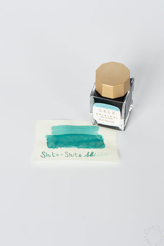 Shito-shito bottled ink with teal swatch card and clear bottle with gold cap