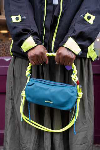 Neon lime braided O-rope strap with round loop and tied ends on teal bag