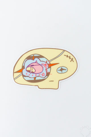 Skull head vinyl sticker with pink character, orange accents, and blue oval marks