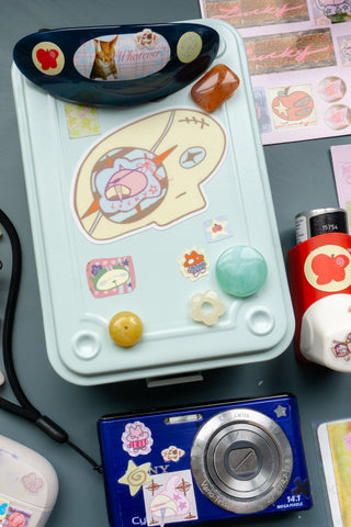 Skull head vinyl sticker on white tray; pink cartoon skull with orange star and blue lines
