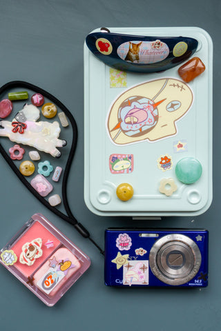 Skull head vinyl sticker on white tray; pink cartoon skull with orange stars and blue accents