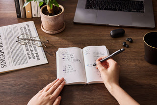 Open notebook with handwritten notes and a pen, grid page layout
