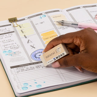 Tombow MONO natural eraser held above a planner page, label facing up
