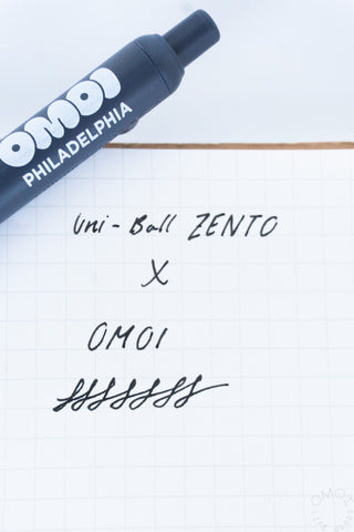 Blue Uni-Ball Zento gel pen with “PHILADELPHIA” text, ink writing on grid paper