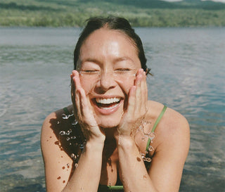 Skincare cleanser usage scene: woman rinsing face with hands