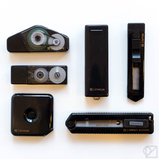 Black mini stationery tools set laid flat, including compact stapler and cutter