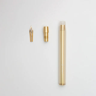 Gold brass dip pen with nib and cap pieces displayed on white background