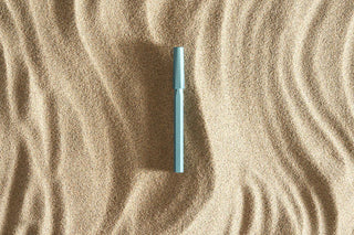 Blue rollerball pen barrel close-up with cap, shown against wavy texture