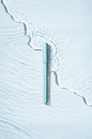 Light blue rollerball pen barrel close-up with cap on textured background