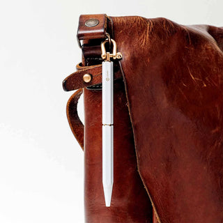 White ballpoint pen attached to a brown leather keychain pouch