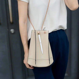White ballpoint pen inside a beige keychain-style pouch held by a person