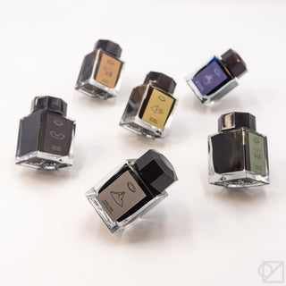 Assorted small ink bottles with black caps and different colored front labels