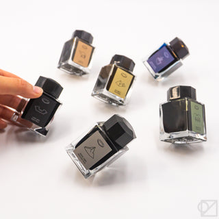 Set of three small ink bottles with dark glass and square black caps