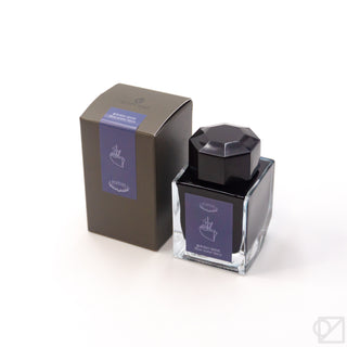 Ink bottle with dark glass, black faceted cap, and light purple label with anchor icon