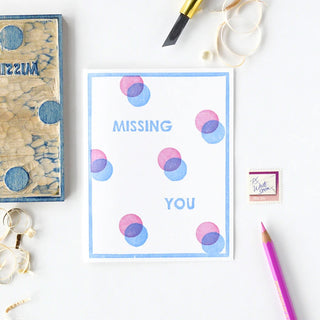 Letterpress card with blue border, multicolor dot circles, 'MISSING' over 'YOU'