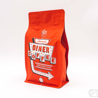 Red coffee bag angled view with Diner Coffee branding and 12oz badge.