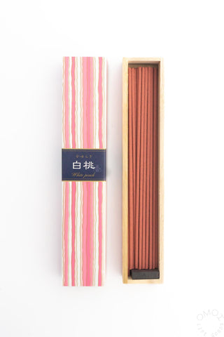 White peach incense sticks in striped sleeve with wooden box of standing sticks