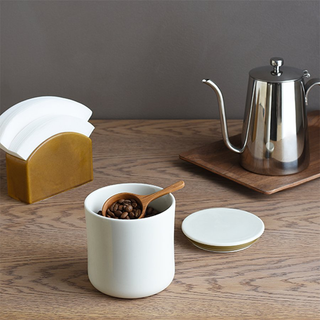 Wood coffee measuring spoon resting in a white cup with coffee beans